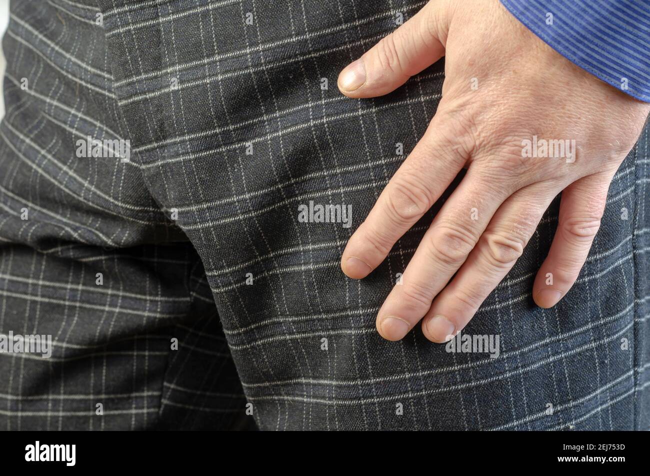 Mano Hombre Adulto en pantalón gris a cuadros y camisa azul primer plano.  La mano se presiona hacia el muslo. Enfoque selectivo Fotografía de stock -  Alamy
