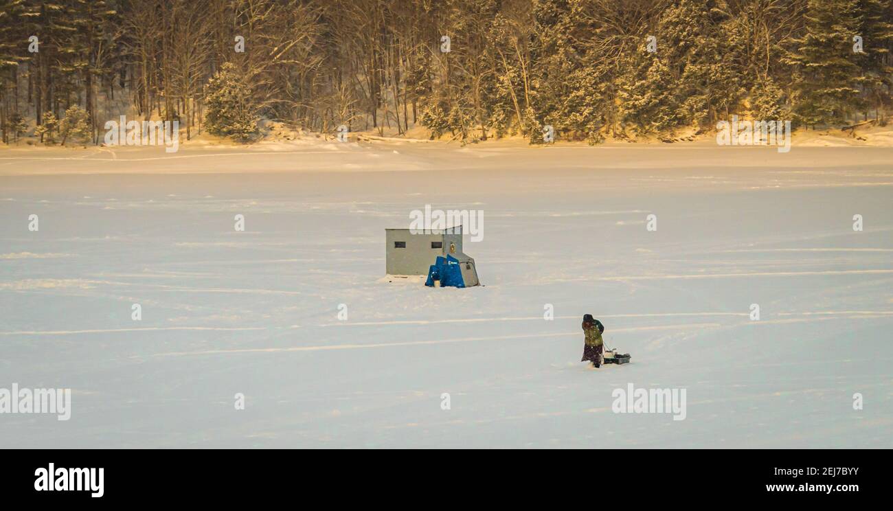 mujer transportando equipo de pesca de hielo en un trineo en un tarde nevada Foto de stock