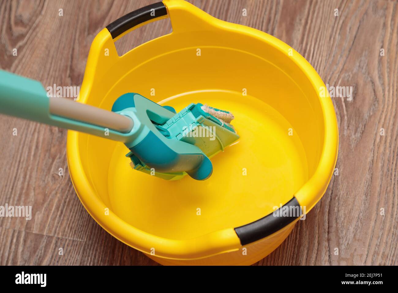 Mopa azul con lavabo amarillo para limpiar suelos. Limpieza de un piso de  una tabla de parquet debajo de un árbol Fotografía de stock - Alamy