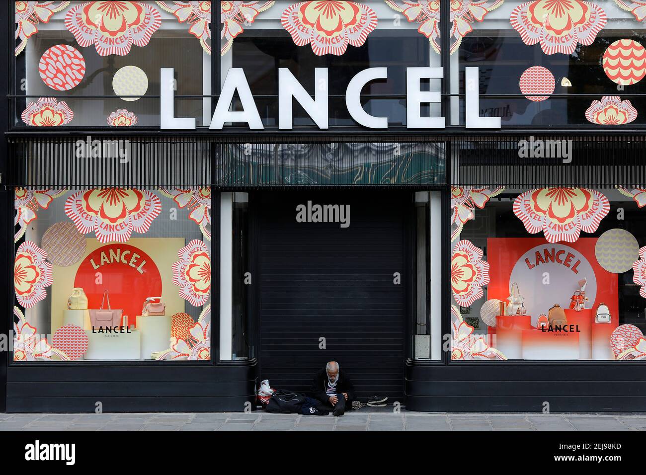 Hombre sin hogar fuera de una tienda de moda en parís, francia Foto de stock