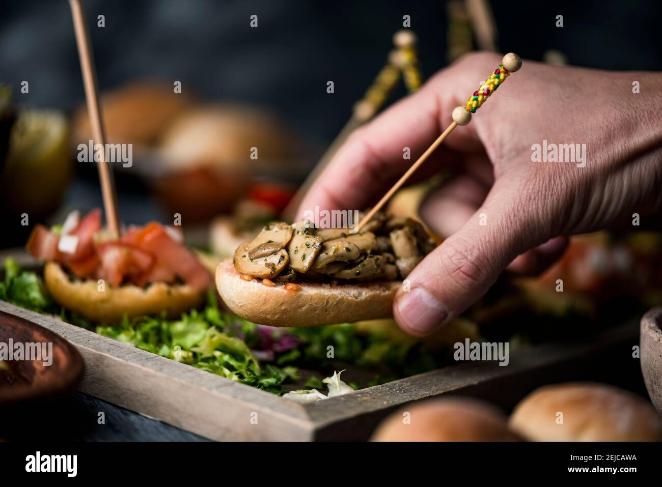 un joven caucásico toma un pincho español vegano de una bandeja con algunos  otros pinchos, hecho con pan con diferentes ingredientes, servido como  bocadillos o un Fotografía de stock - Alamy