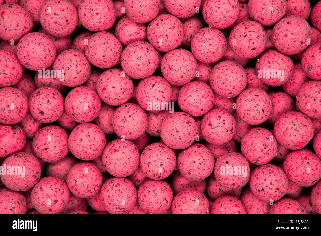 Pequeñas bolas rosas dulces. Boilies redondos usados como cebo de pesca de carpa. Fondo rosa abstracto Foto de stock