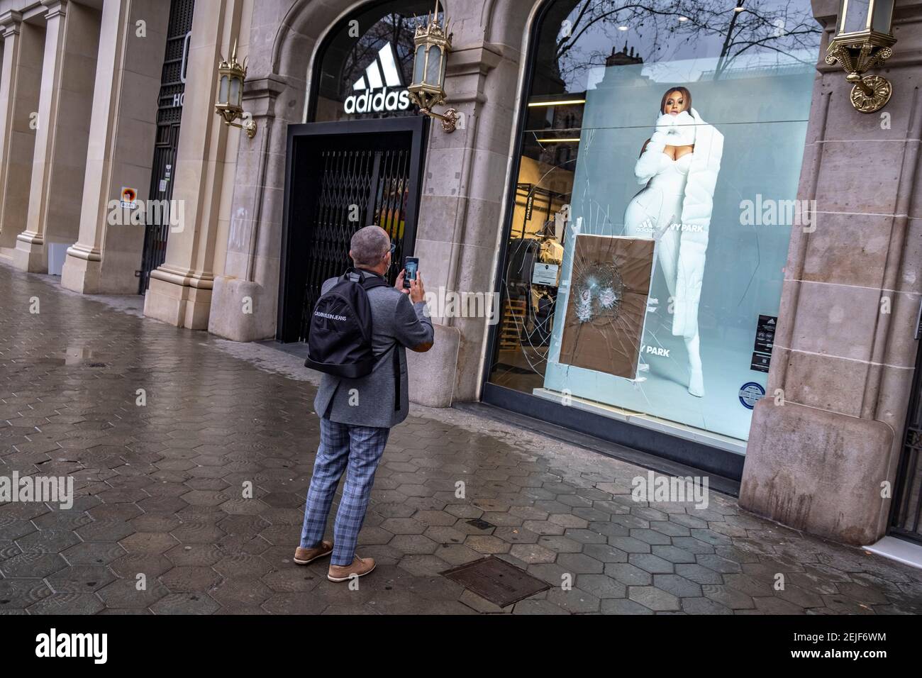 Barcelona, España. 22 de febrero de 2021. Se ve a un hombre haciendo fotos  de los daños a la tienda Adidas en el Passeig de Gràcia.más de 50 tiendas  han sufrido daños