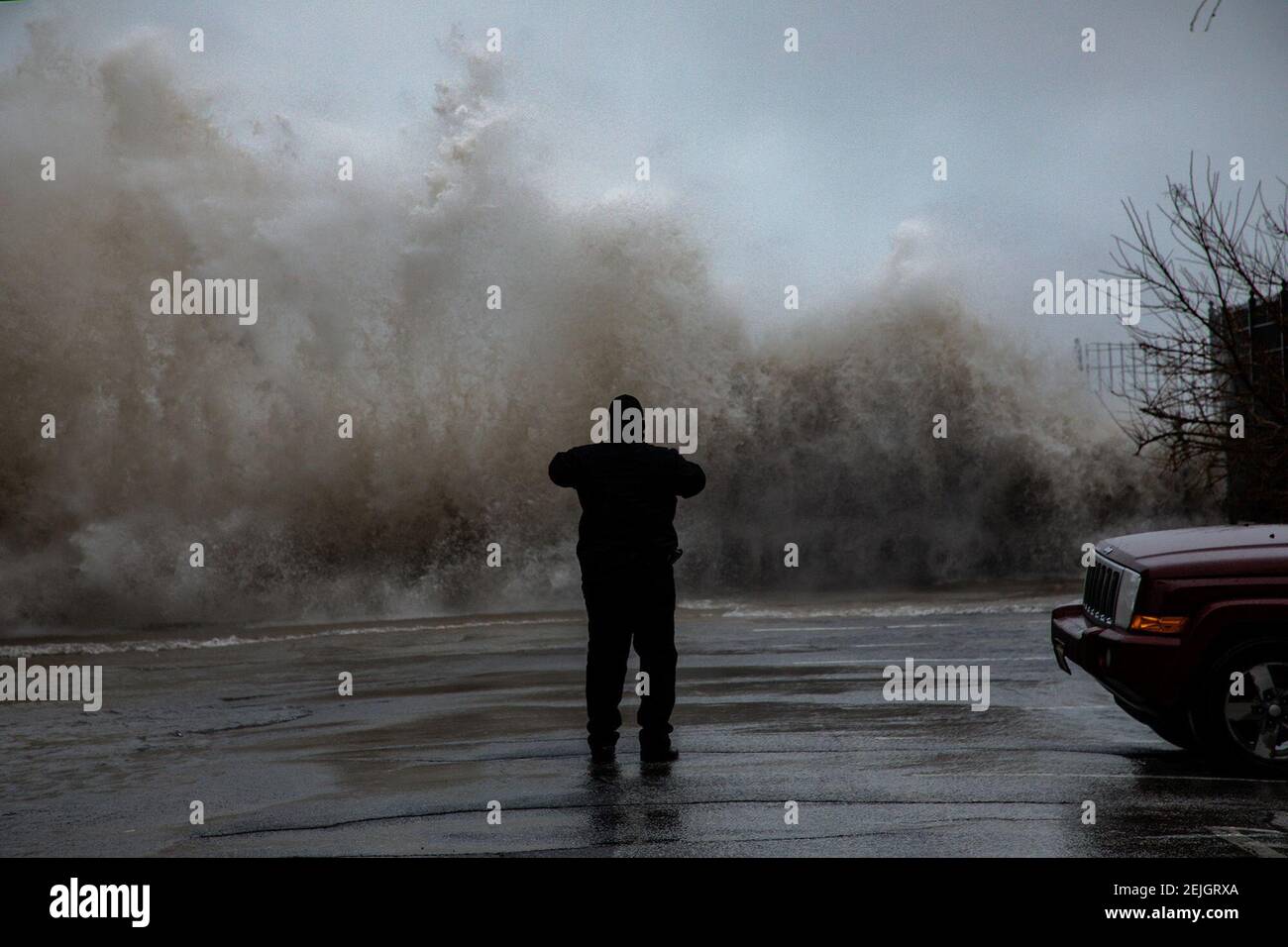 Un trabajador de Chicago City toma fotos de olas rompiendo en East 73rd Street mientras su tripulación trabaja un área inundada cerca de South Shore Drive el 11 de enero de 2020. (Zbigniew Bzdak/Chicago Tribune/TNS) Foto de stock
