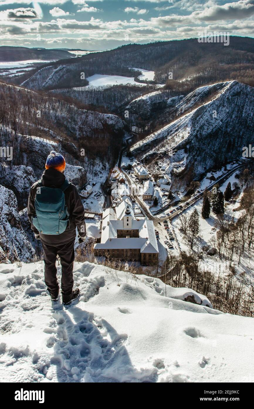 Hombre disfrutando de la vista aérea de invierno de Svaty Jan pod Skalou, pequeño pueblo pintoresco en Bohemia Central, República Checa. Monasterio escondido bajo los acantilados Foto de stock