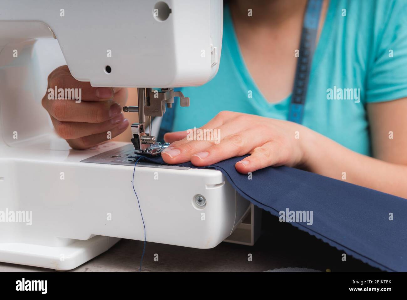 Mujer alegre coser mientras se sienta en su lugar de trabajo en taller de moda Foto de stock