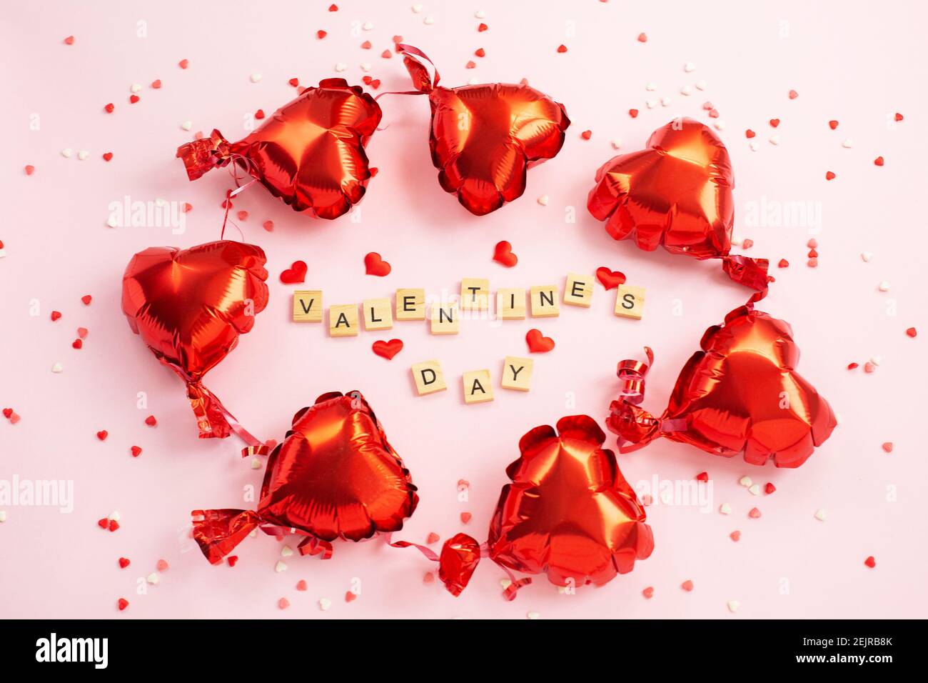 La palabra día de San Valentín de bloques de letras y corazones rojos Globos de aceite alrededor. Romántico, concepto de día de San Valentín. Vista superior. Foto de stock