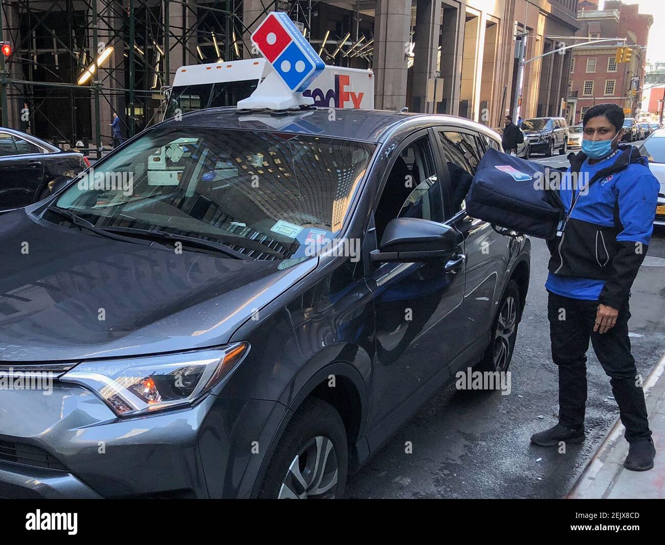 Un conductor de Domino's Pizza se prepara para hacer una entrega cerca de  la Bolsa de Nueva York en Broad Street en el bajo Manhattan. Los mercados  de valores subieron más del