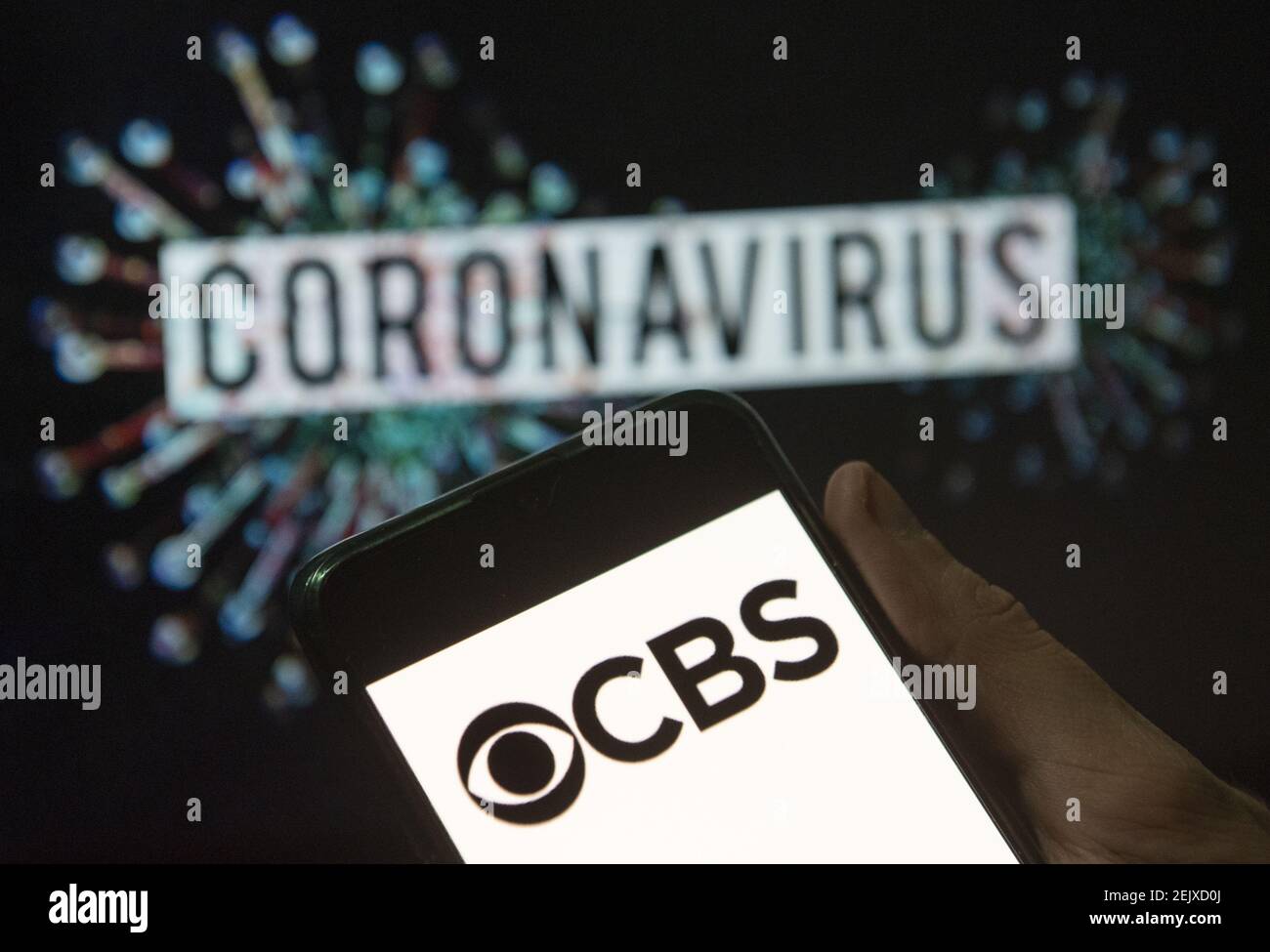 En esta ilustración de la foto el logotipo de la cadena de radio y  televisión comercial en inglés americano CBS visto en un smartphone con un  modelo de ordenador del coronavirus COVID-19