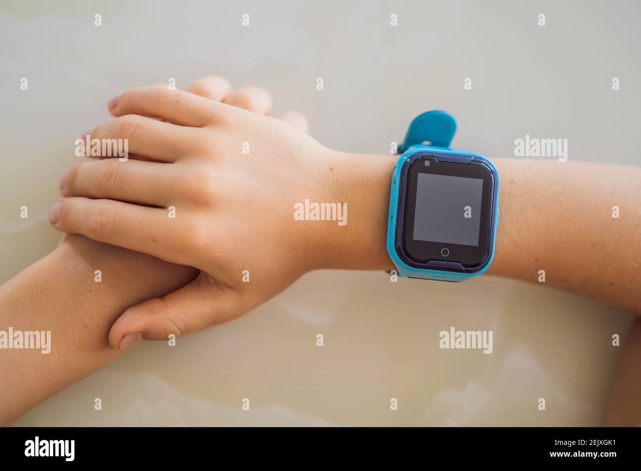 Un niño sentado en la mesa y mirando un reloj inteligente. Reloj  inteligente para la seguridad del bebé. El niño hace lecciones escolares, escuchar  música, llamar Fotografía de stock - Alamy