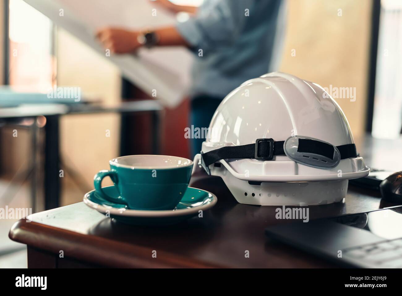 cascos de seguridad y taza de café en la mesa en la construcción del sitio.  Arquitecto, Ingeniero leer la planificación de fondo borroso Fotografía de  stock - Alamy