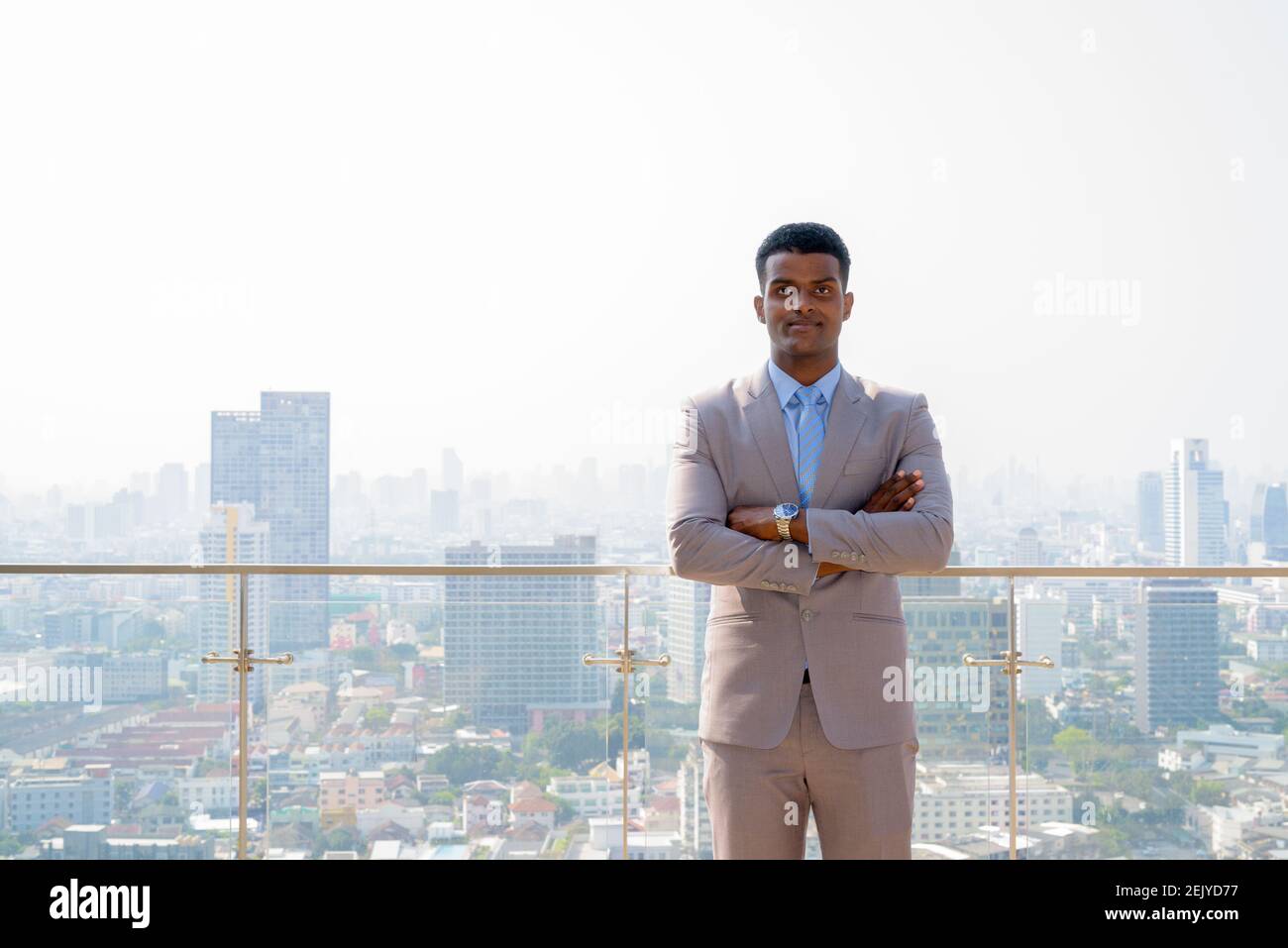 Retrato de un joven hombre de negocios africano con un traje que parece seguro con los brazos cruzados Foto de stock