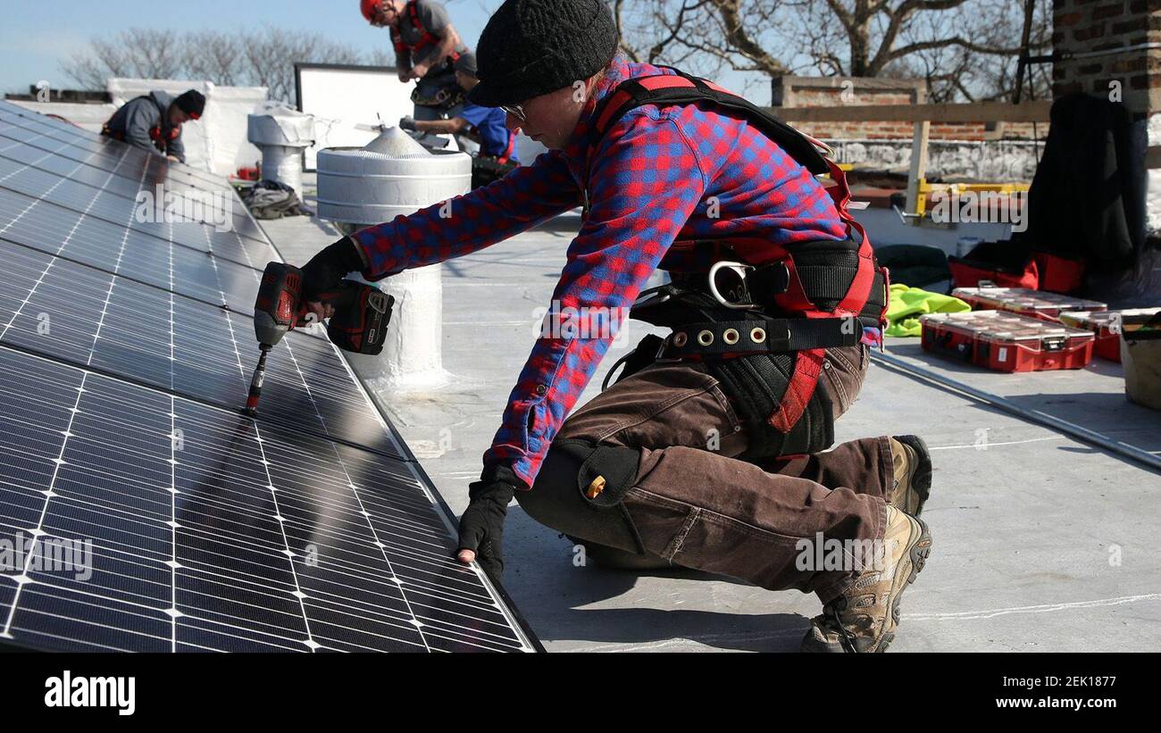 Jennifer Raber y otros trabajadores de Ailey Solar, una empresa con sede en el barrio McKinley Park en Chicago, instalan paneles solares en el techo plano de una residencia en el lado suroeste de Chicago el lunes, 2 de marzo de 2020. (Terrence Antonio James/Chicago Tribune/TNS) Foto de stock