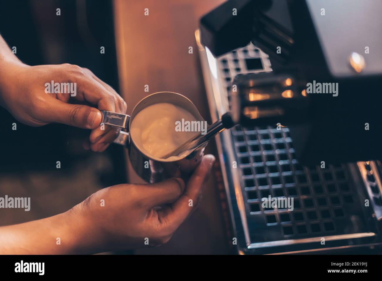 Barista calienta el vapor de leche para hacer lattes en la cafetería. Foto de stock
