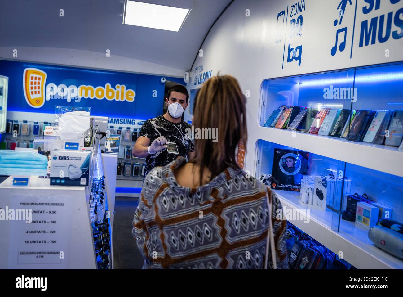 Se ve a un trabajador de una tienda móvil atendiendo a un cliente mientras  se lleva una máscara como precaución durante la reapertura de negocios en  medio de las restricciones de Coronavirus.