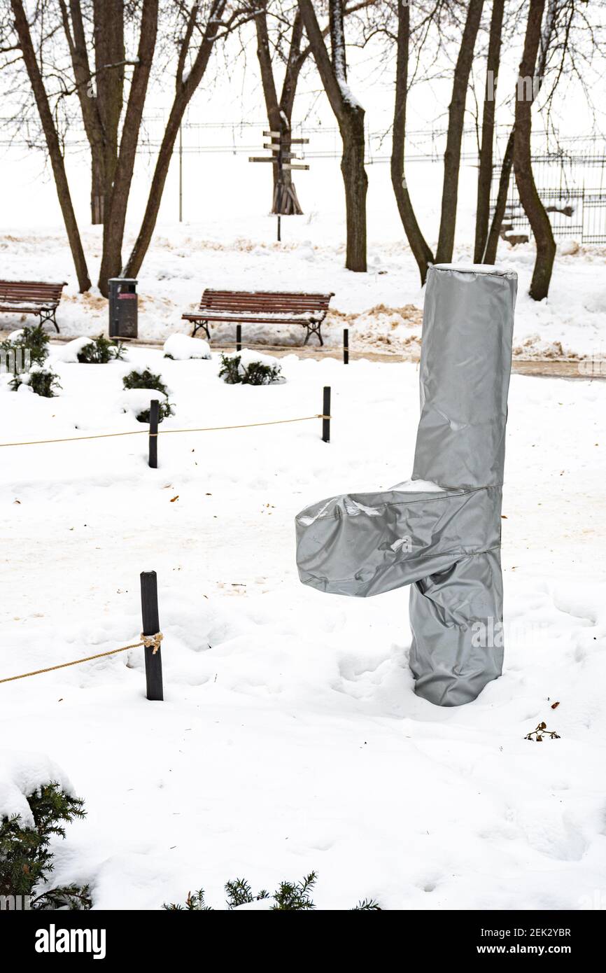 Fuente en un parque cubierto con bolsa de plástico de protección para proteger de la nieve, la escarcha y la temperatura fría en invierno o primavera, vertical Foto de stock