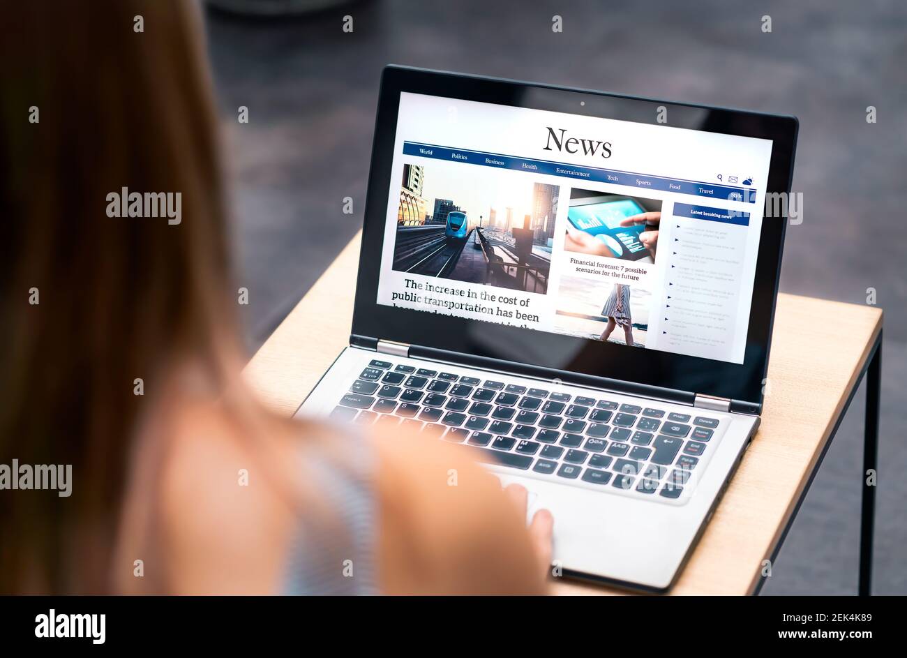 Sitio web de noticias en pantalla de portátil con artículo en línea y titular. Mujer leyendo periódico o revista con ordenador. Portal digital de publicaciones web. Foto de stock