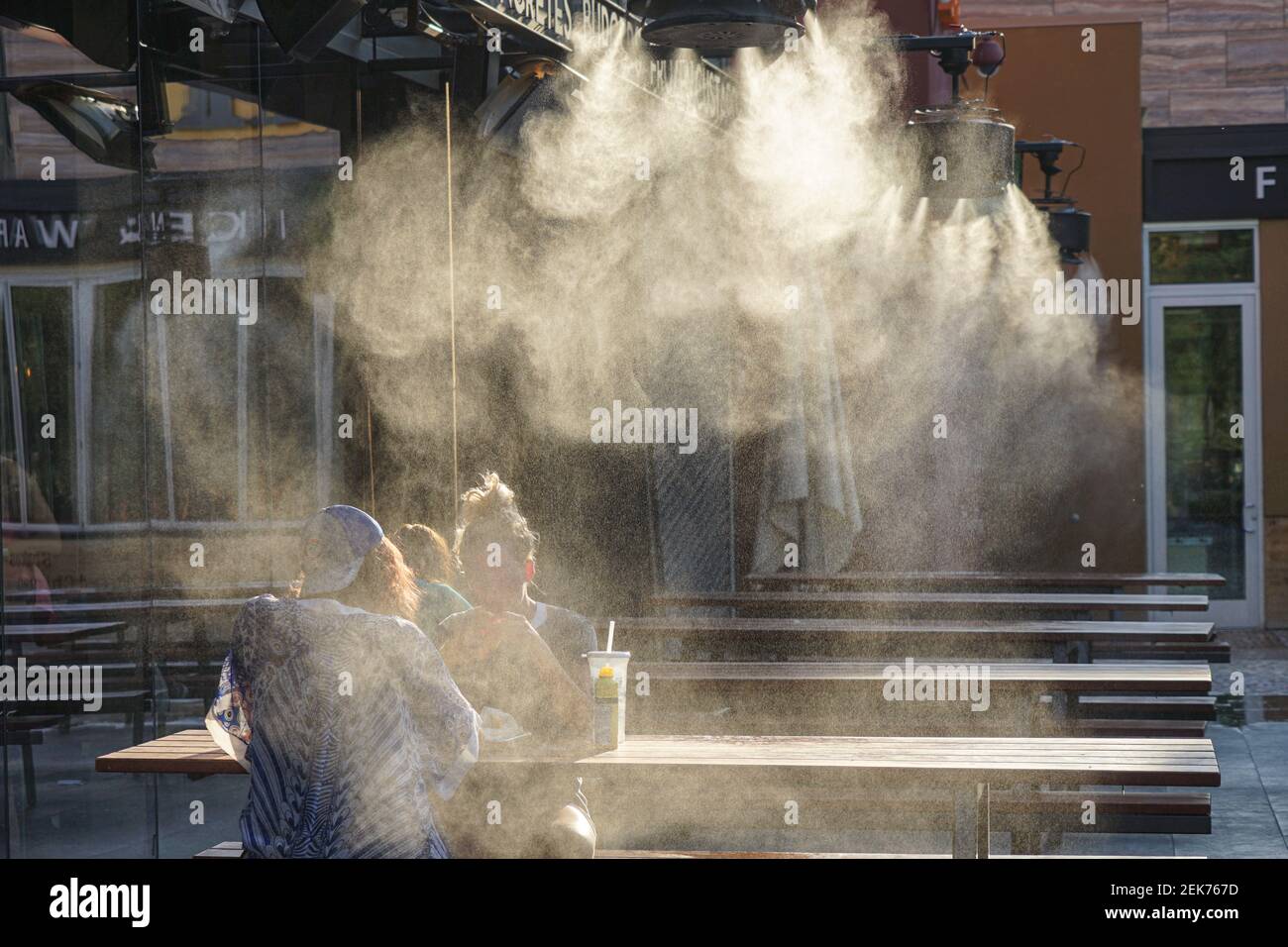 Personas sentadas bajo la neblina de un sistema de enfriamiento por neblina En un café al aire libre en las Vegas Foto de stock