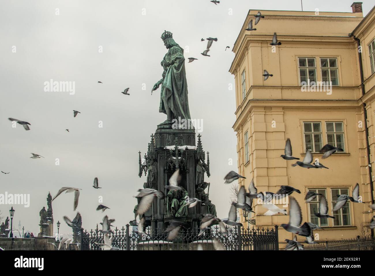 Praga, República Checa. 02-23-2021. Estatua del rey Carlos IV en la Plaza de la Cruz llena de palomas voladoras, cerca del puente de Carlos en Praga. Bronce neogótico Foto de stock