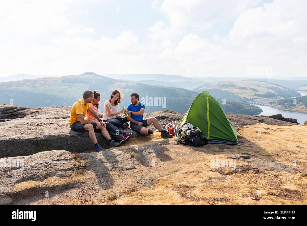 Hombres y mujeres amigos excursionistas acampando en la cima de la montaña durante vacaciones Foto de stock