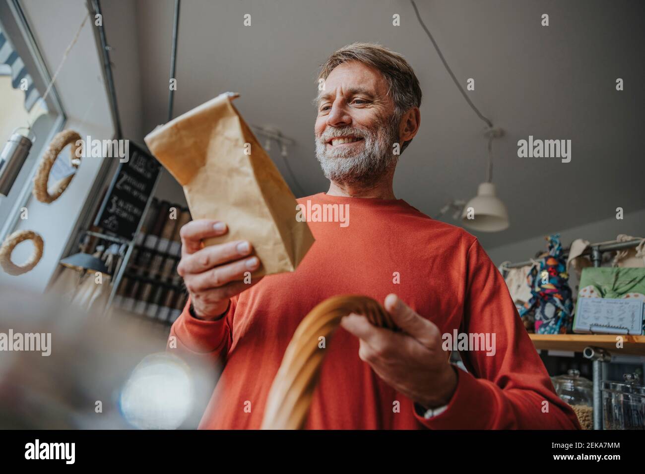 Hombre maduro feliz mirando el paquete marrón mientras que está parado  adentro tienda al por menor Fotografía de stock - Alamy