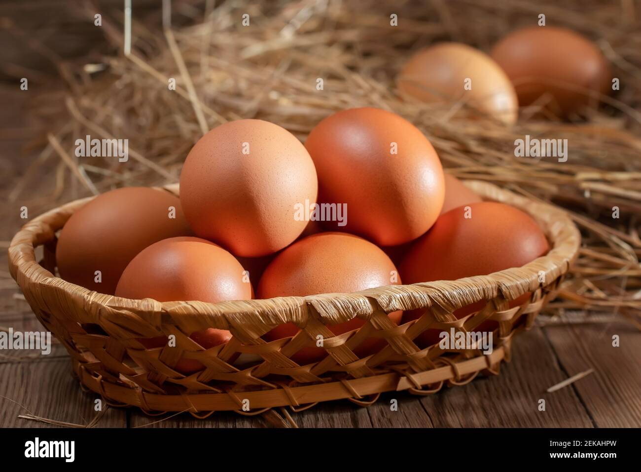 Huevos frescos de pollo en una cesta y en un nido de heno en un granero. Foto de stock