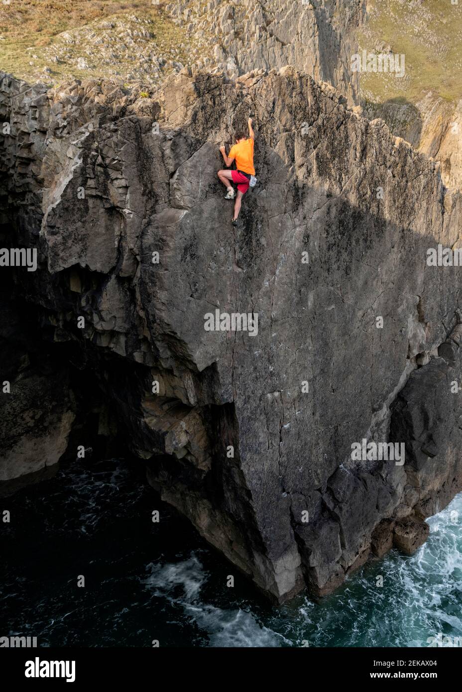 Escalador masculino maduro que alcanza en la cima del acantilado Foto de stock