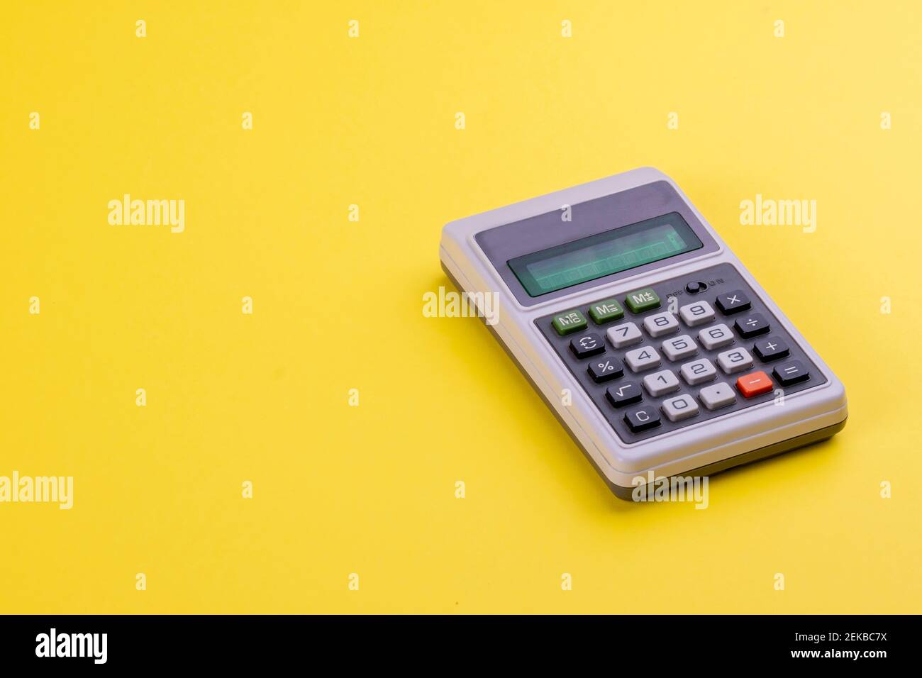 Objetos retro en negocios y educación. Una calculadora de época con pantalla digital y botones numéricos sobre fondo amarillo Pantone 2021. Contando Foto de stock