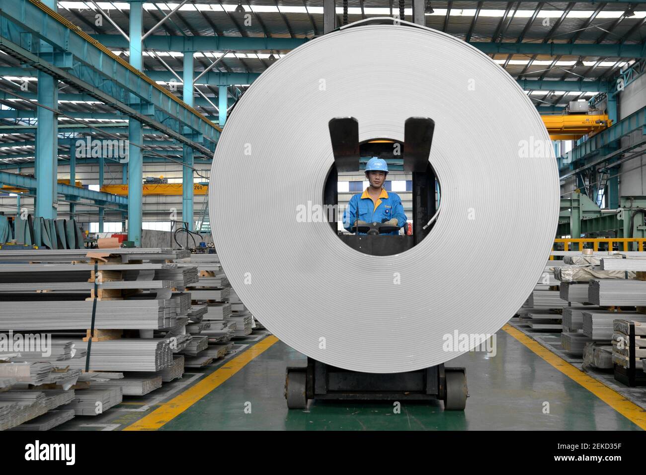 WUXI, CHINA - 11 DE AGOSTO de 2020 - un trabajador de una empresa de hierro  y acero levanta productos de acero inoxidable plano. Ciudad de Wuxi,  Provincia de Jiangsu, China, 11