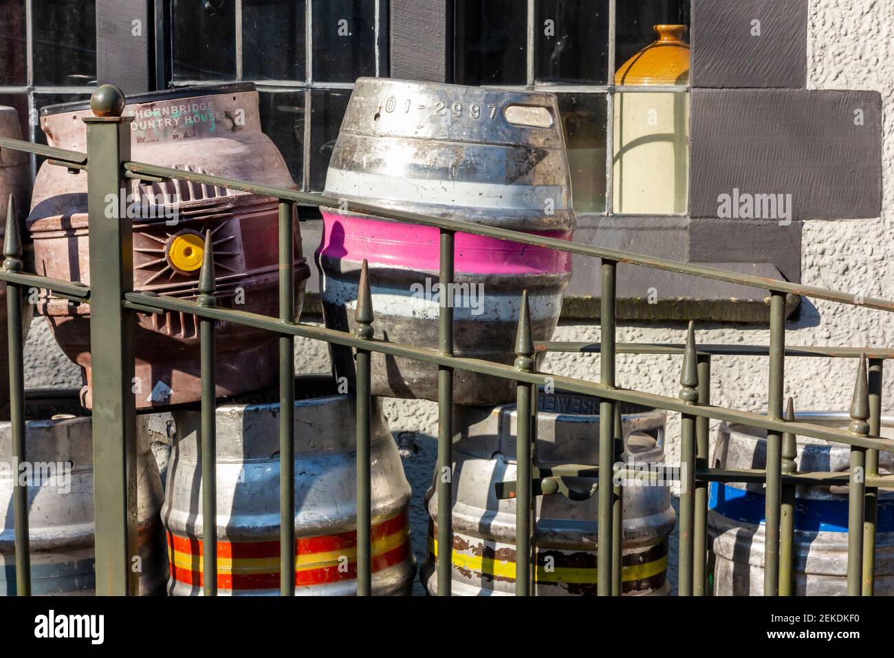 Barriles de cerveza de metal apilados fuera de un pub para su recogida y reutilización. Foto de stock