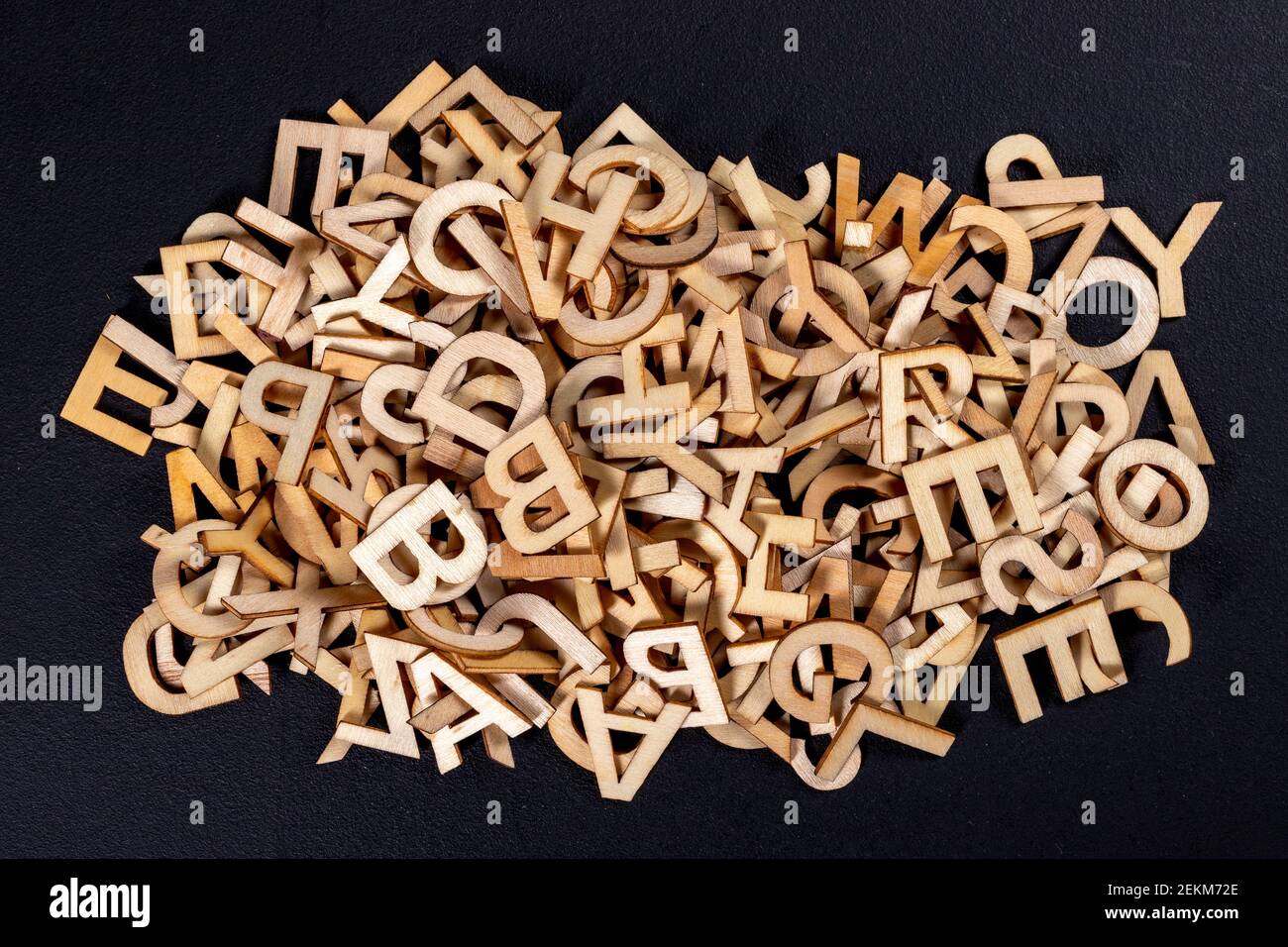 Una pila de pequeñas letras de madera sobre una mesa oscura. Las letras se  describen para organizar inscripciones y palabras. Fondo oscuro Fotografía  de stock - Alamy
