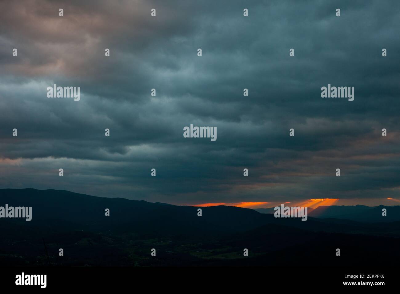 Los rayos de la luz que fluye brillan de las nubes superiores durante Puesta de sol sobre las Montañas Blue Ridge en Virginia Foto de stock