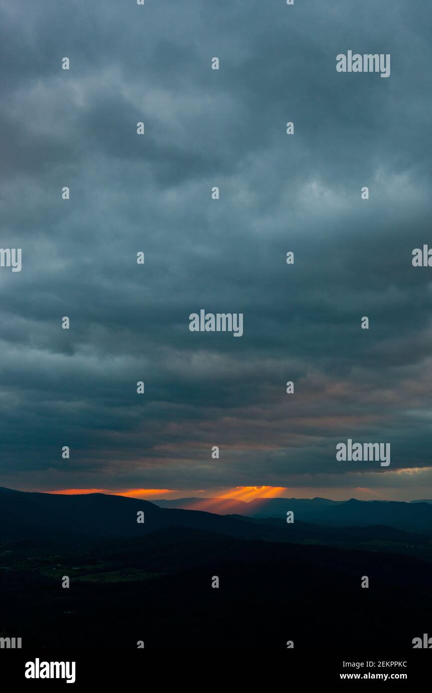 Los rayos de la luz que fluye brillan de las nubes superiores durante Puesta de sol sobre las Montañas Blue Ridge en Virginia Foto de stock