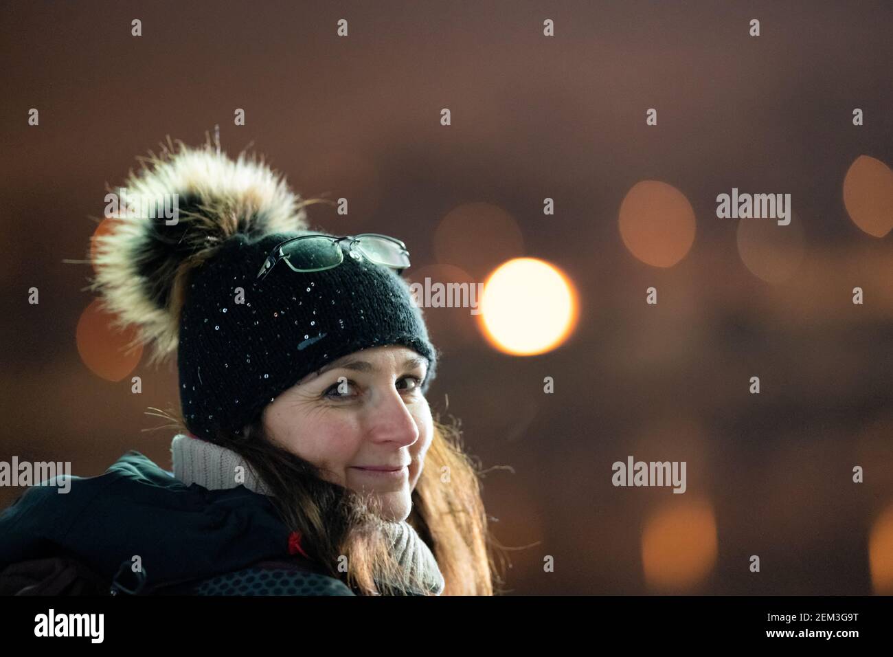 Mujer blanca con sombrero de punto y gafas en el sombrero, mirando y sonriendo a la cámara. Feliz y alegre estado de ánimo invernal. Foto de stock