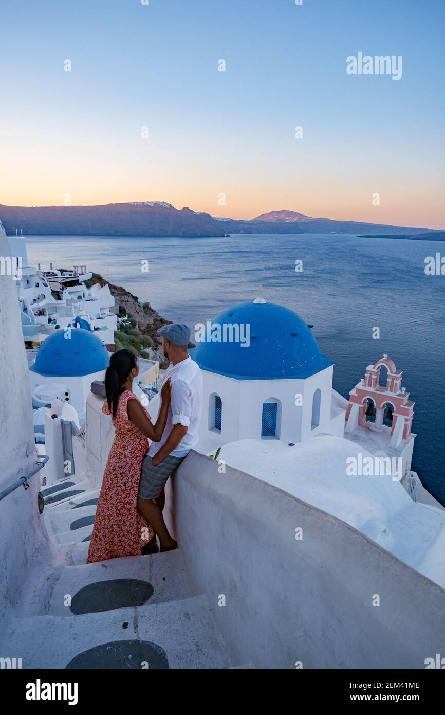 Santorini Grecia, pareja de edad europea y asiática de vacaciones en el pueblo griego de Oia Santorini Grecia, vacaciones de lujo Santorini. Hombre y mujer de edad media viendo la