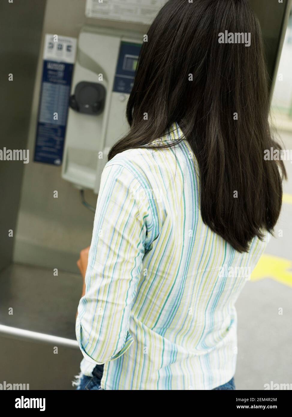 Vista trasera de una adolescente en frente de un teléfono de pago Foto de stock