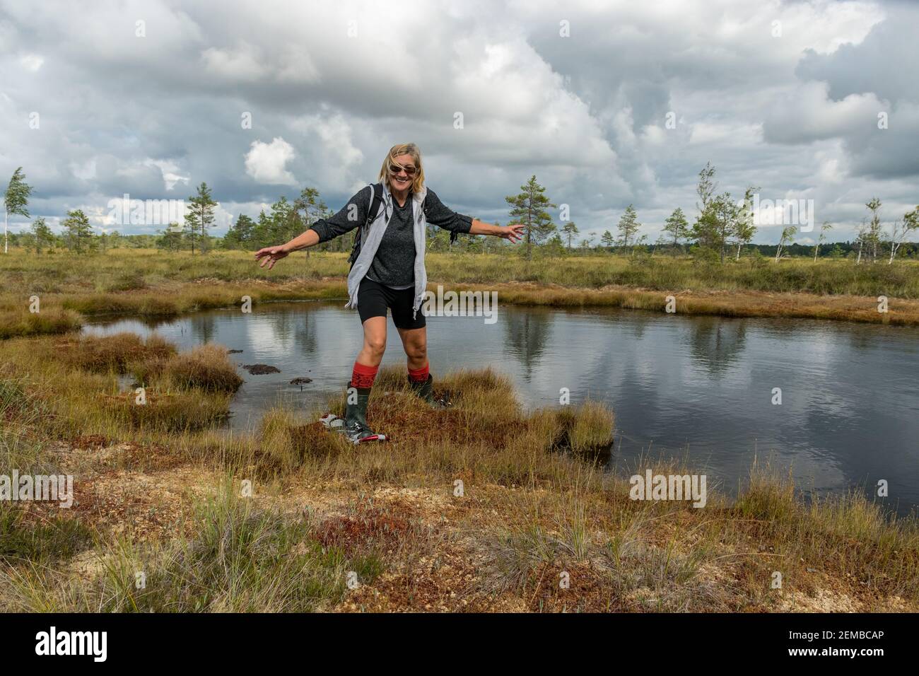 paisaje veraniego en el pantano, una mujer camina por el pantano con  zapatos de pantano y botas de goma naranja en sus pies Fotografía de stock  - Alamy