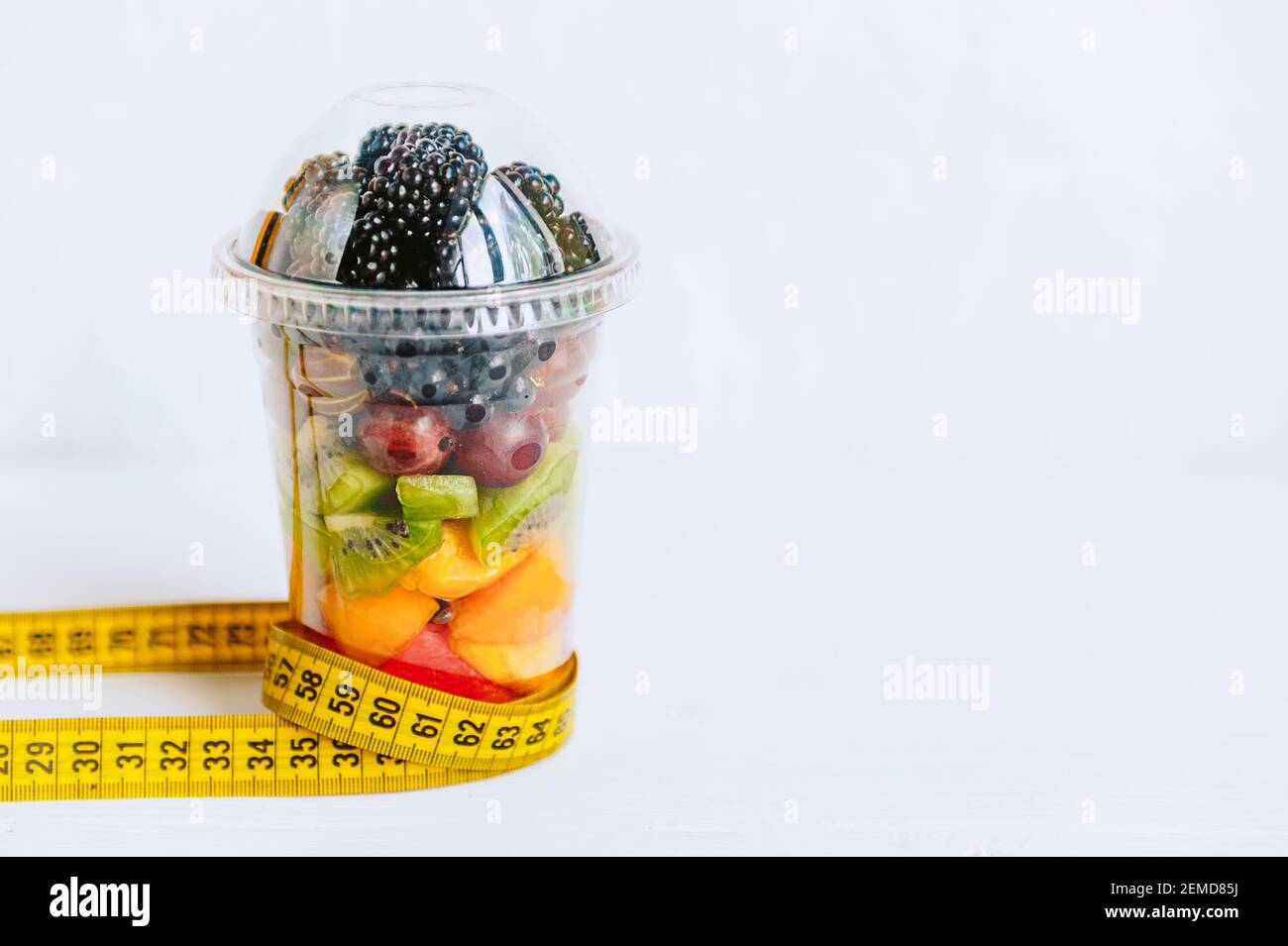 Fruta en un vaso, una campana y una cinta para medir el cuerpo