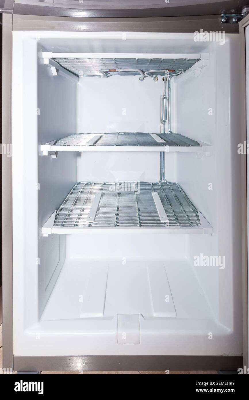 Congelador doméstico vacío y descongelado con puerta abierta. Foto de stock