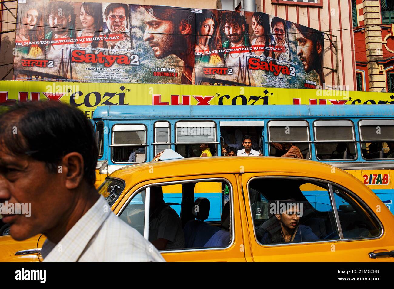 Escena callejera con un taxi amarillo Embajador, autobús y la gente en el centro de Kolkata, India. Foto de stock
