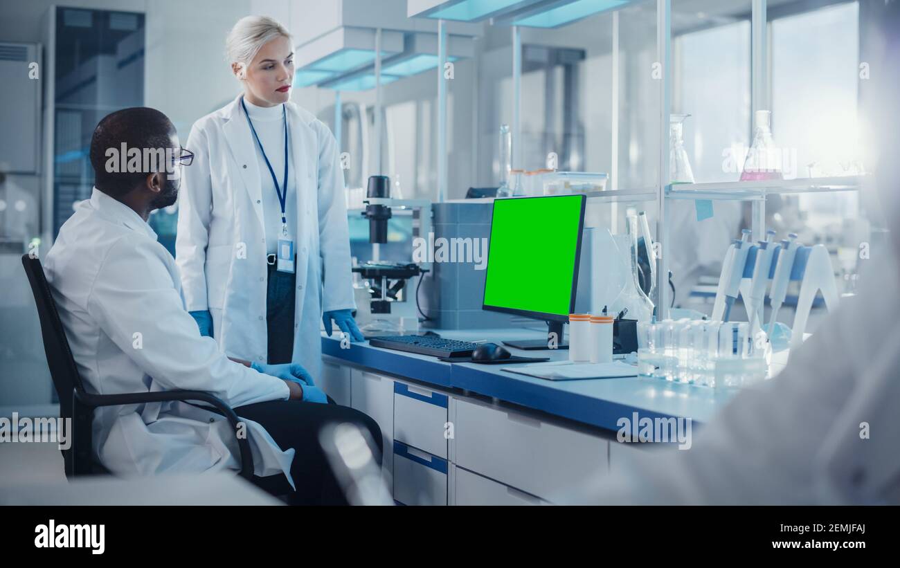 Laboratorio moderno de Investigación médica: Dos científicos utilizan la computadora con pantalla verde de la llave del croma, los especialistas discuten la tecnología innovadora. Avanzado Foto de stock