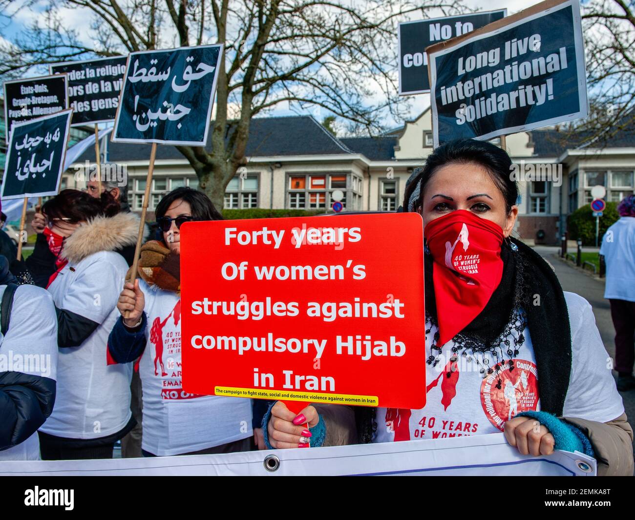 Un manifestante es visto cubriendo su rostro con una bufanda roja mientras  sostiene un cartel diciendo cuarenta años de lucha de mujeres contra Hijab  obligatorio en Irán durante la protesta. En el