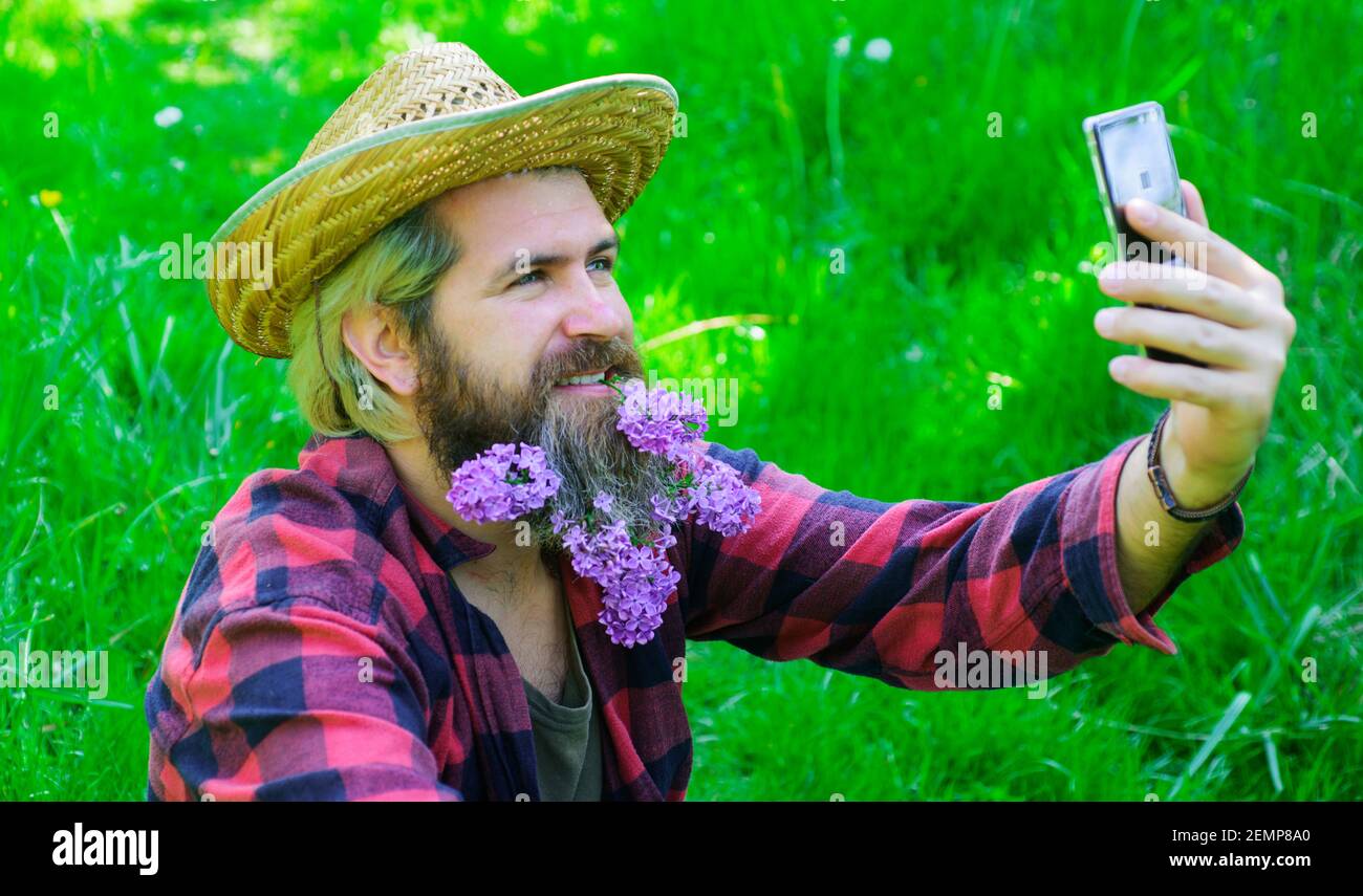 Hombre guapo con barba de flores haciendo selfie en el smartphone. Hipster hace fotos selfie en el teléfono. Tipo barbudo con barba decorada Fotografía de stock - Alamy Hombre guapo con barba de flores haciendo selfie en el smartphone. Hipster hace fotos selfie en el teléfono. Tipo barbudo con barba decorada Fotografía de stock - Alamy