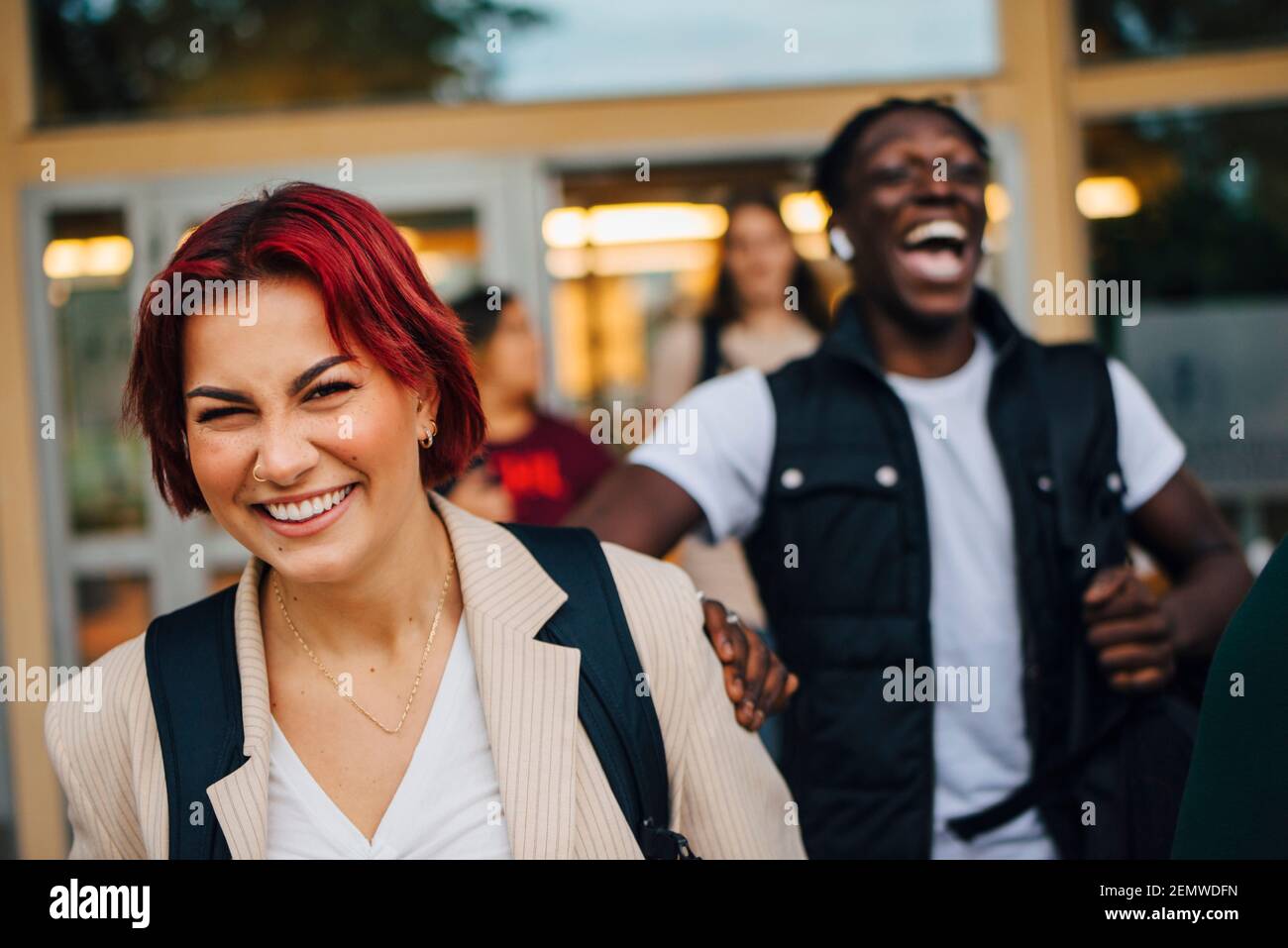 Redhead estudiante riendo con amigos durante la puesta de sol Foto de stock