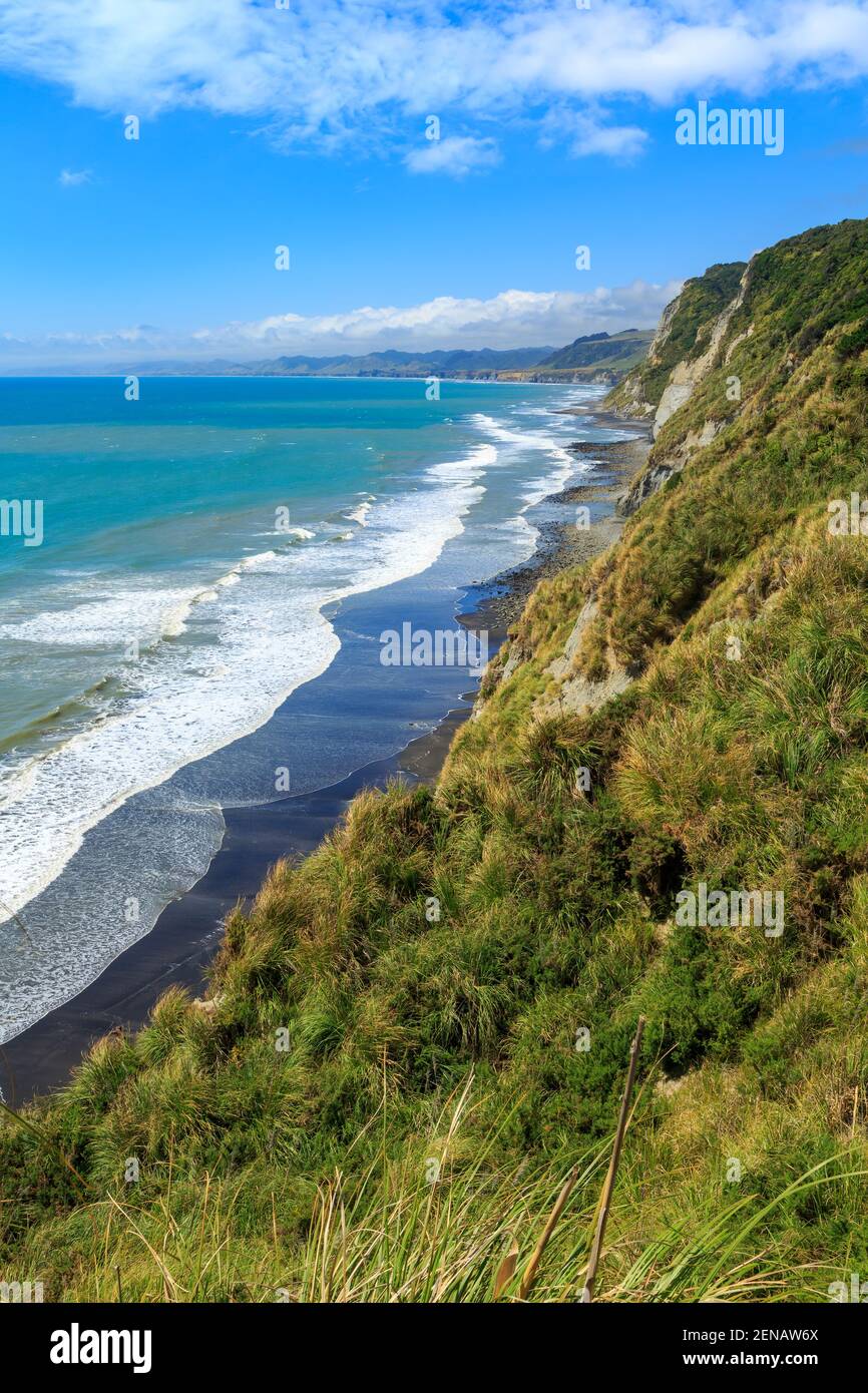 La costa en Whitecliffs, Taranaki Region, Nueva Zelanda. Grandes rollos de surf en tierra en la playa de arena negra Foto de stock