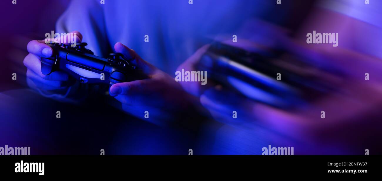 jugadores jugando consola de videojuegos. controlador en manos primer plano. banner de luces de neón Foto de stock