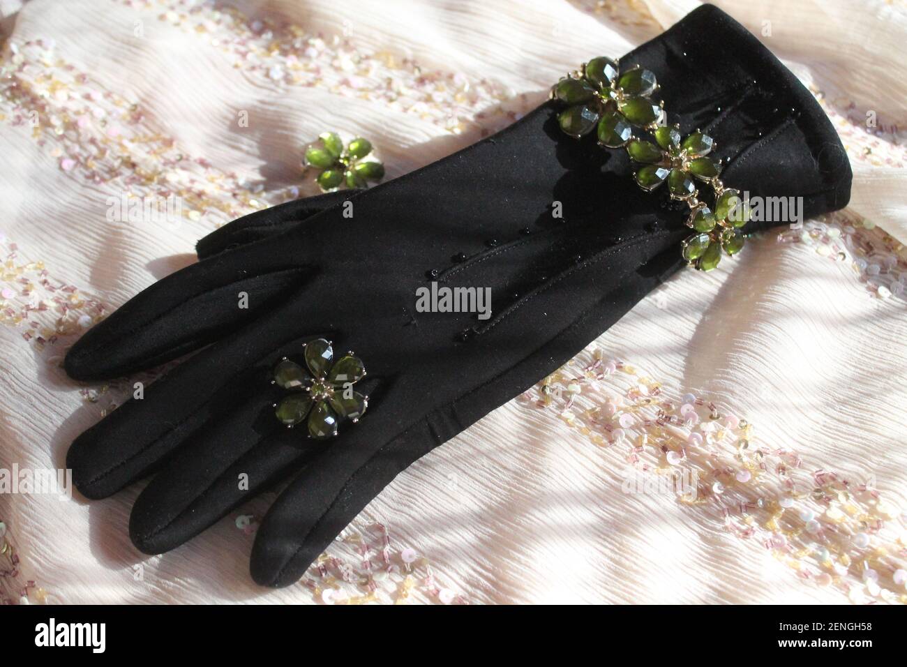 hermosa pulsera de joyas y anillo en forma de margarita acostarse en el guante negro de la mujer Foto de stock