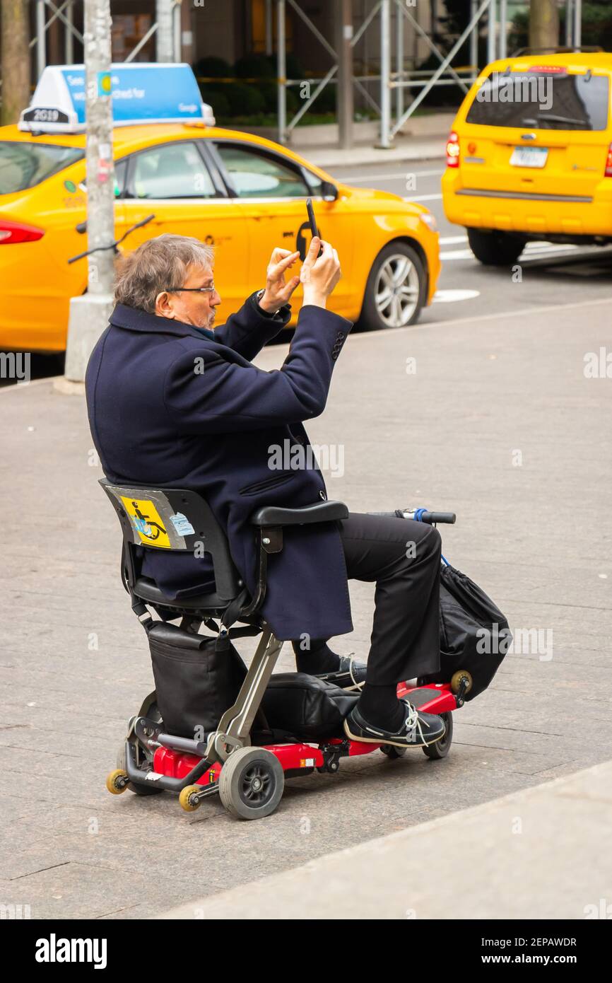 turista hombre discapacitado en silla de ruedas toma una foto por teléfono  Calle Nueva York Fotografía de stock - Alamy