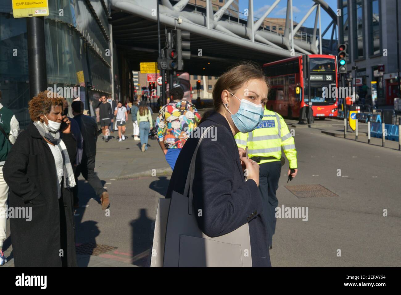 Una mujer que lleva una máscara facial como protección contra el coronavirus (covid-19) pasa por una calle en London Bridge, Londres, Reino Unido Foto de stock