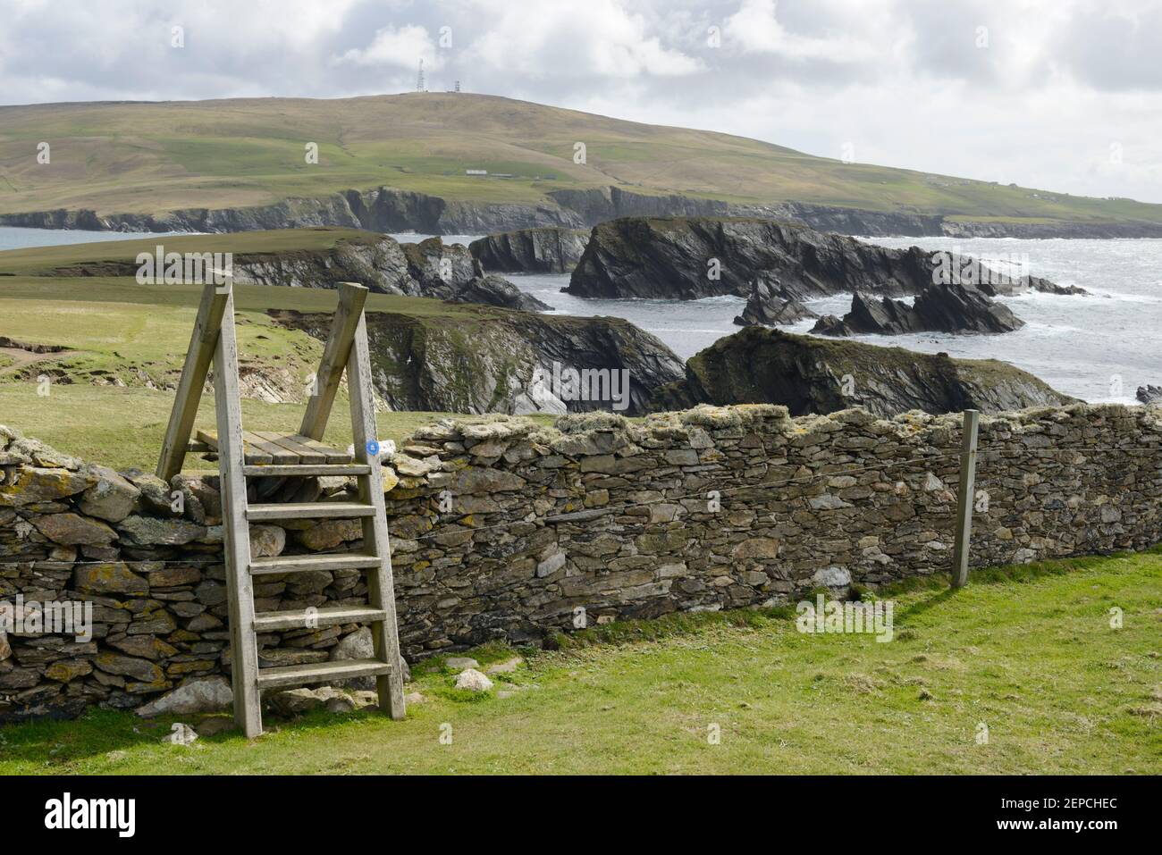 Un stile de madera que se extiende a lo largo de una pared de piedra seca en la isla de San Niniano, Shetland. Foto de stock